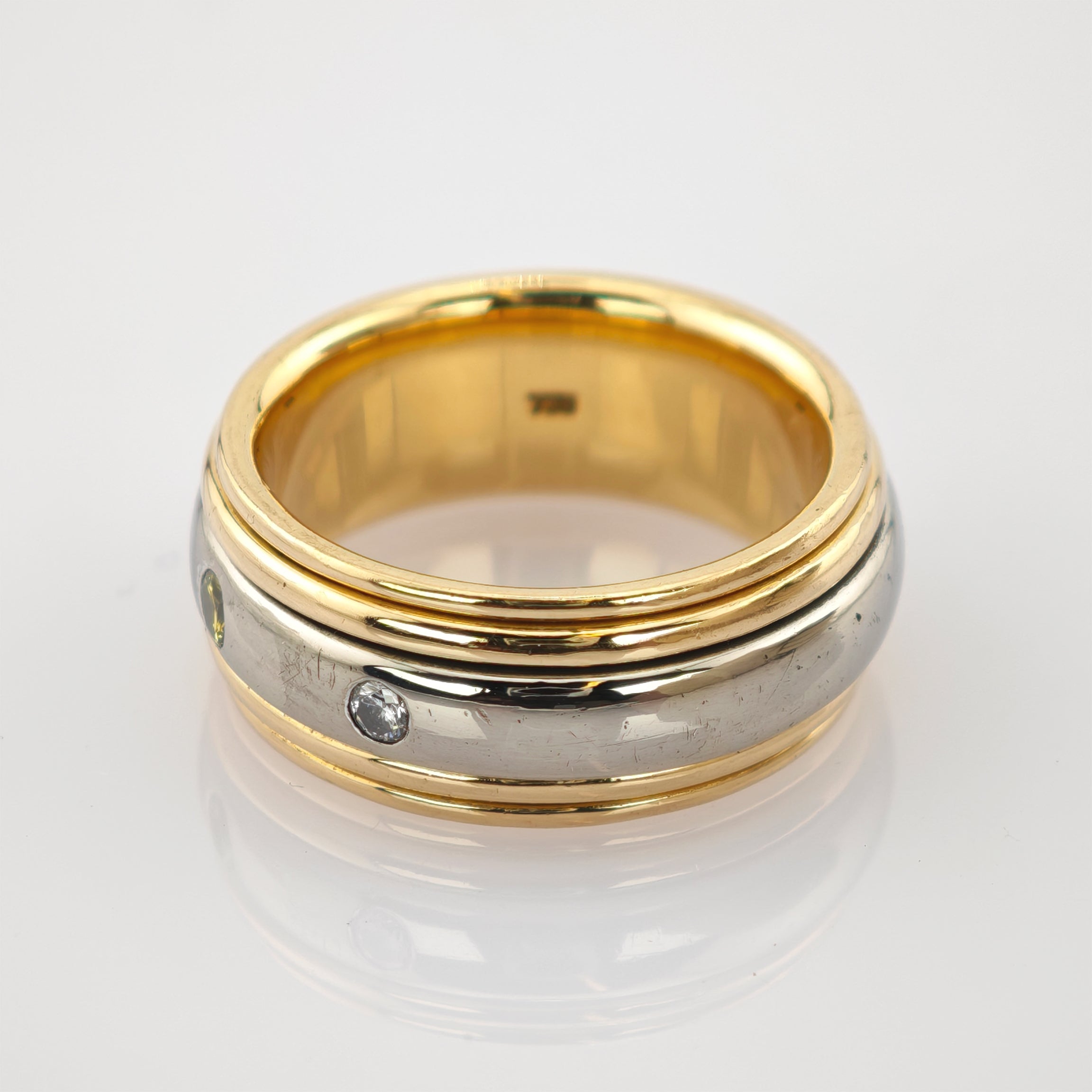 Zweifarbiger Ring mit Gelbgold-Innenband, silbernem Mittelteil und zwei Edelsteinen.