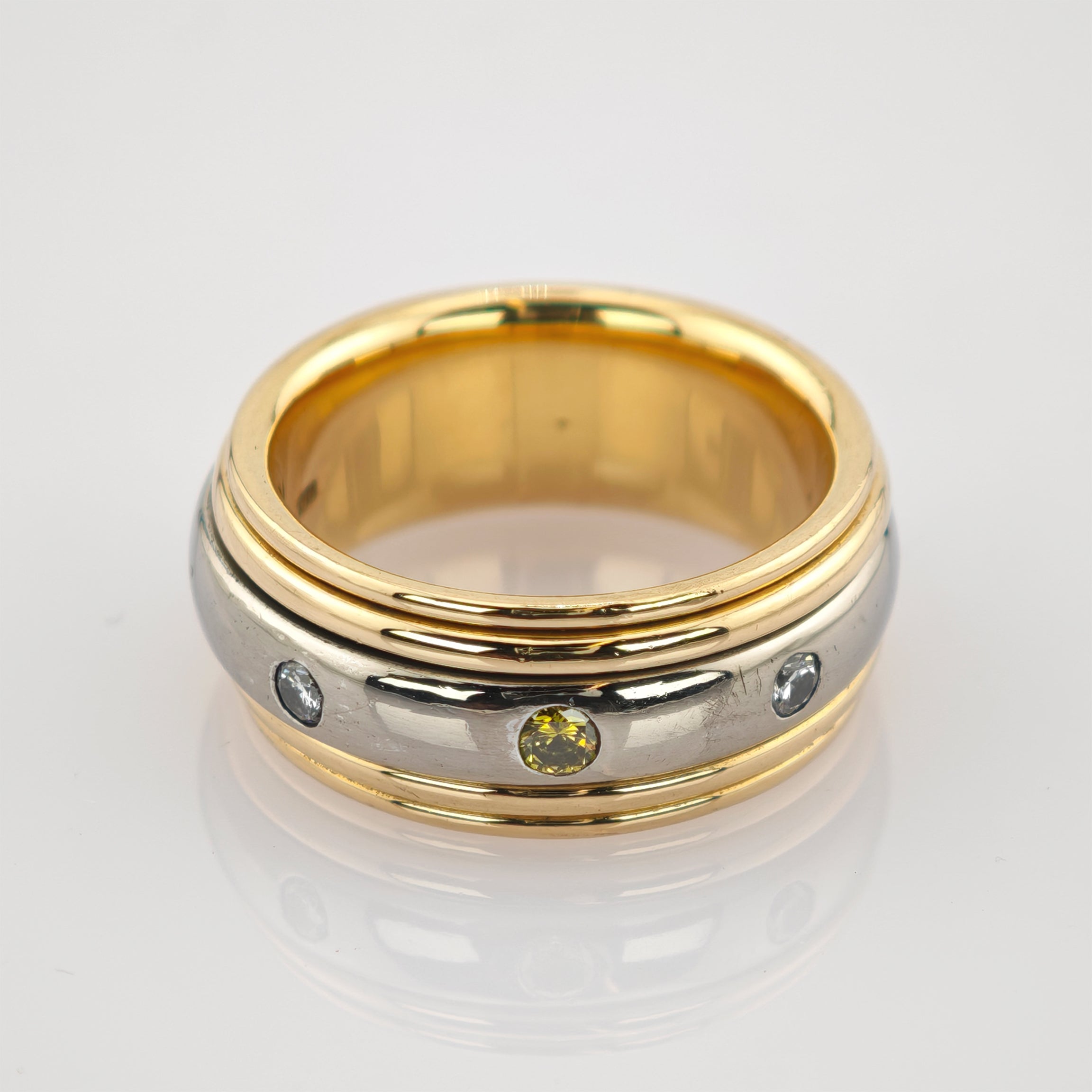 Zweifarbiger Ring mit silbernem Band und drei eingelassenen Edelsteinen in Gelb und Klar.